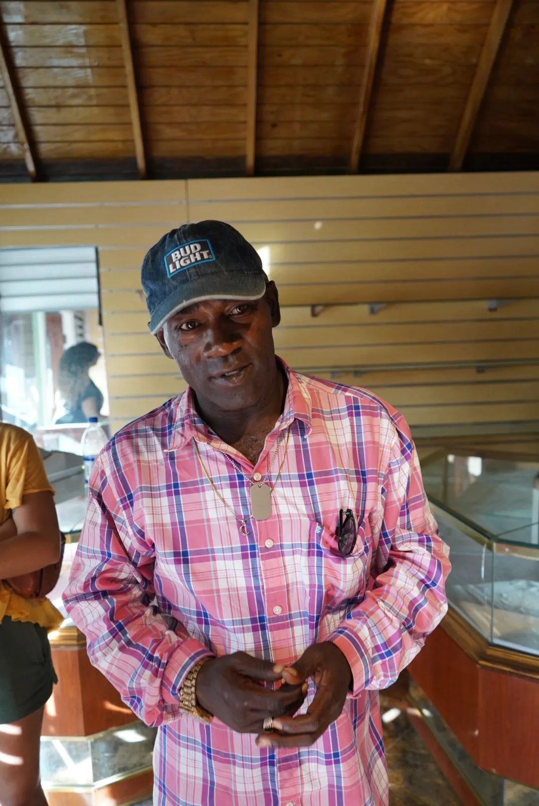 a man in a pink shirt and hat standing in front of a counter