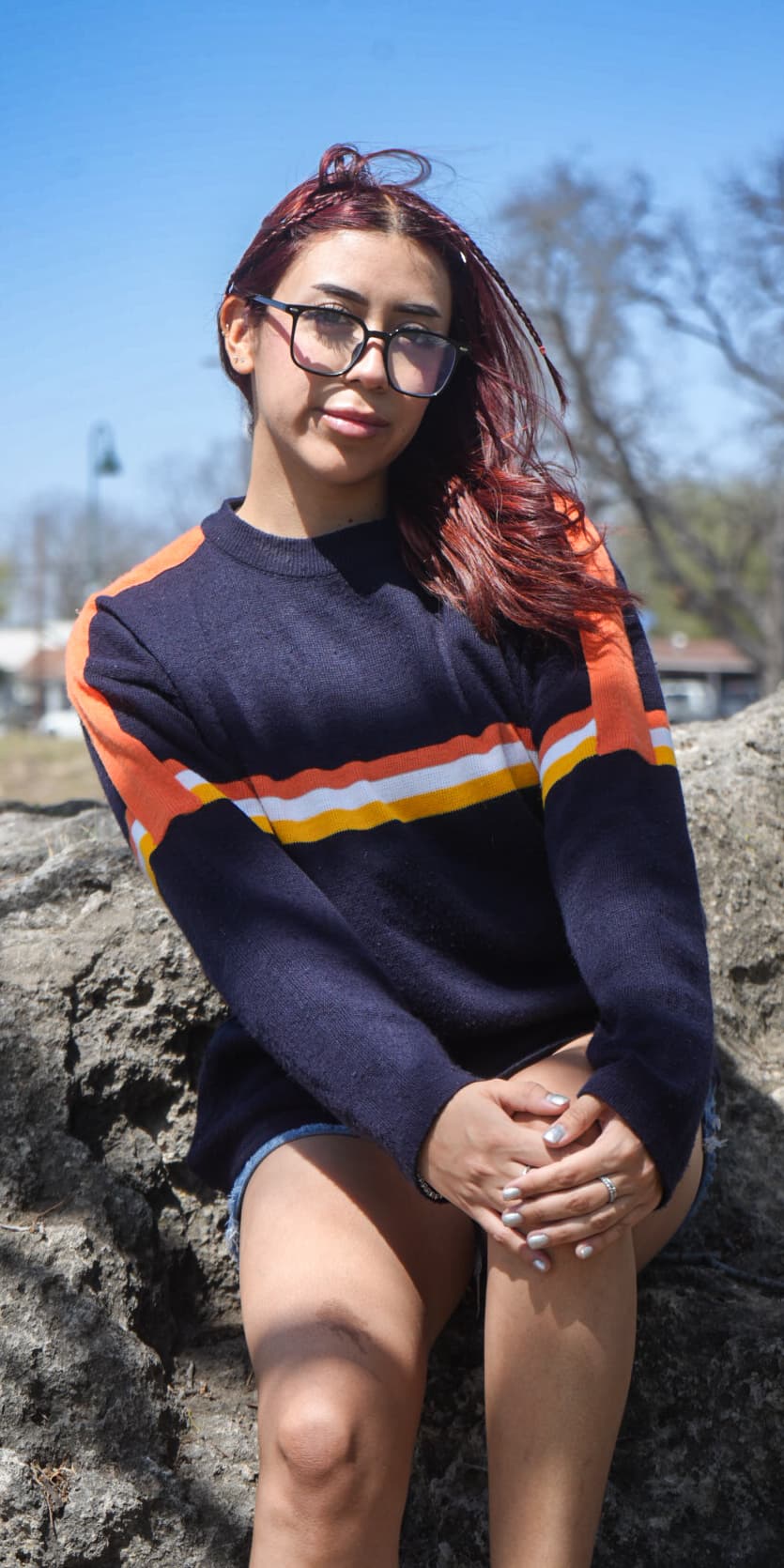 a woman sitting on a rock wearing glasses