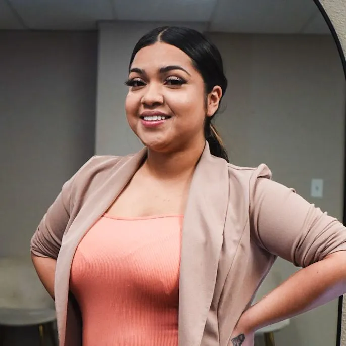 a woman in a pink top and tan jacket