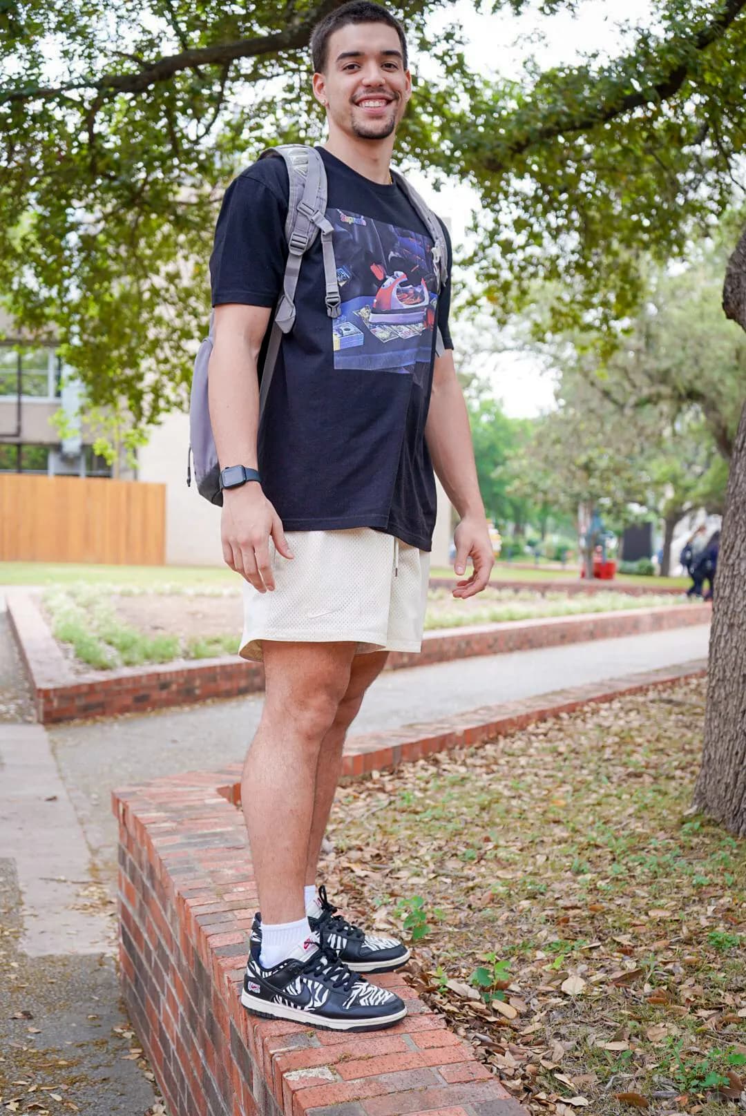 a man standing on a brick wall wearing a backpack