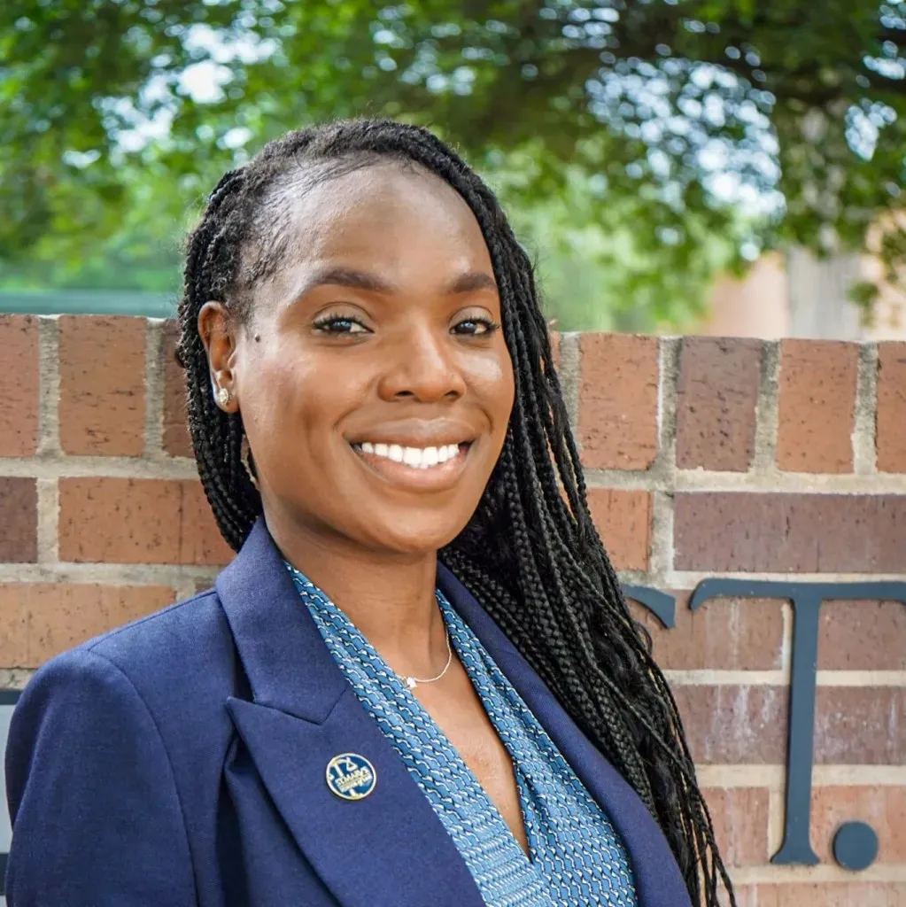 a woman with braids smiles at the camera