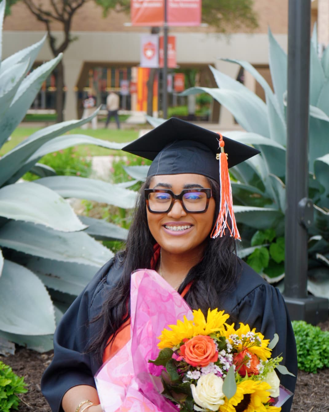 a woman in a graduation gown holding a bouquet